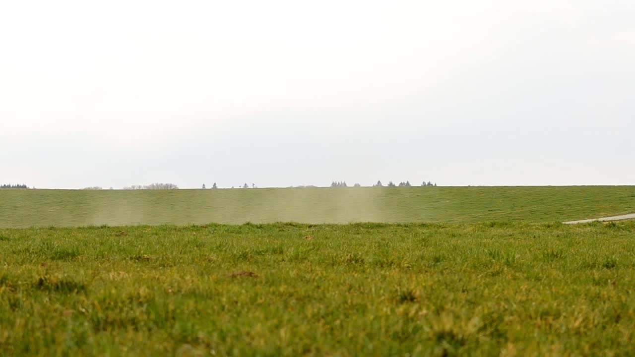 Polvere di una strada sterrata sollevata dal vento sui verdi prati della campagna europea