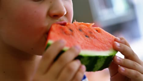 boy having watermelon in kitchen