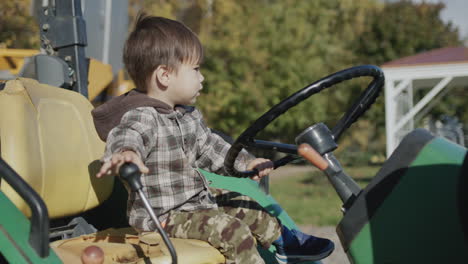 Asian-kid-playing-behind-the-wheel-of-an-old-tractor-on-a-farm