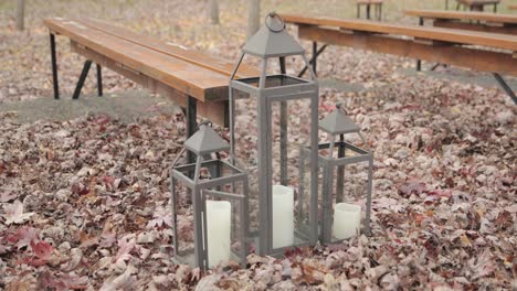 beautiful fall décor of lanterns with white candles, leaves on the ground and benches for a outdoor wedding at bean town ranch in ottawa