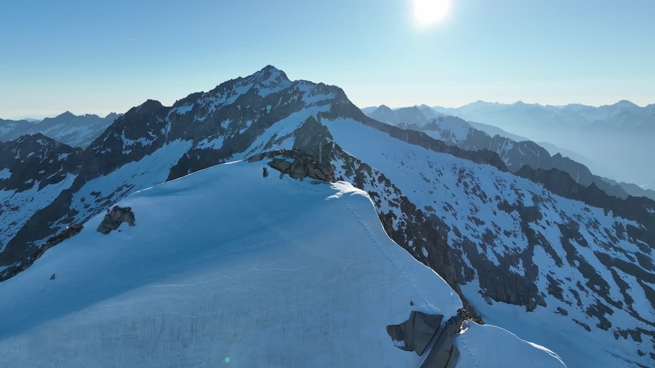Circling drone orbit shot around a jagged summit overlooking a glacier in Austria's breathtaking Alps mountain range