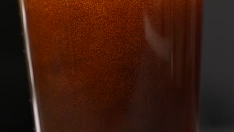 Close-up of coffee bubbles rising in a glass, creating a soothing effect