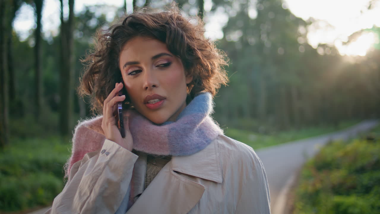 Elegant woman calling cellphone in sunny evening forest closeup. Girl talking