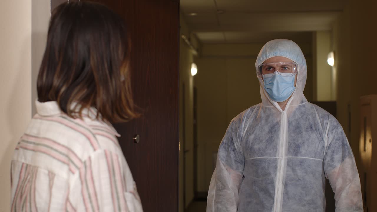 un trabajador de la salud con un traje de protección, sosteniendo una jeringa y un cartel que dice'manténgase saludable y vacúnese'