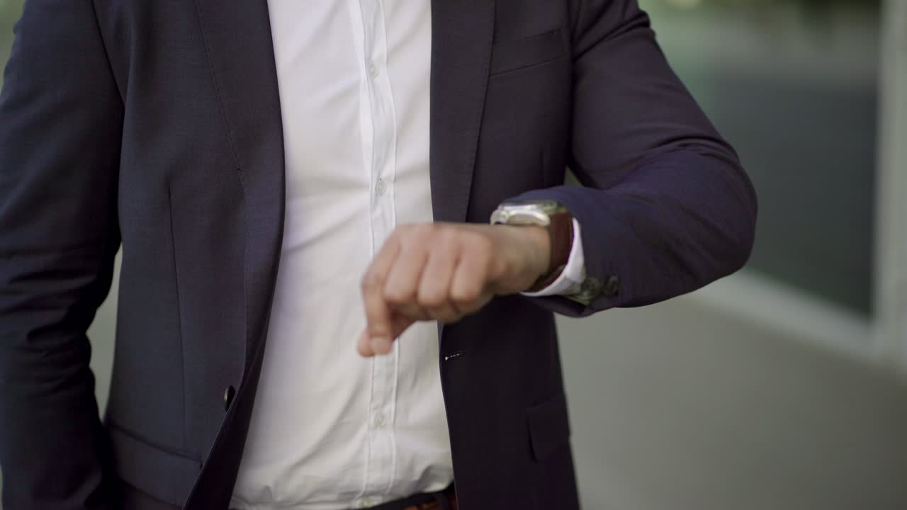 Cropped shot of businessman checking wrist watch outdoor