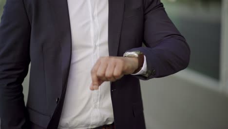 cropped shot of businessman checking wrist watch outdoor