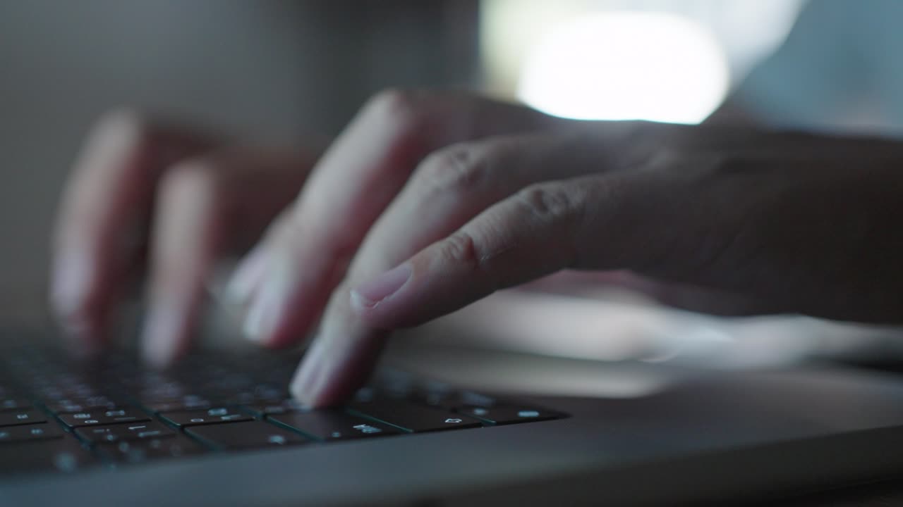 close up hands working overtime typing research laptop office desk at night