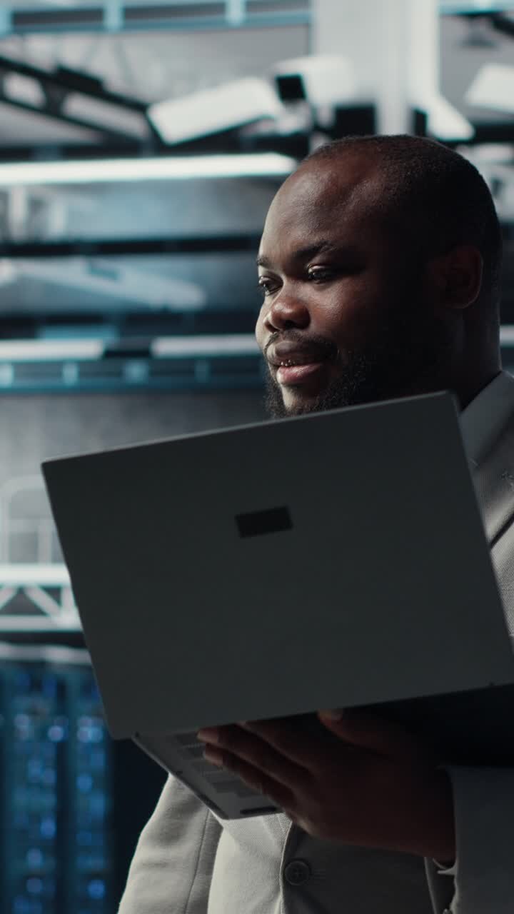 Vertical video Server room worker auditing systems for vulnerabilities using software on laptop