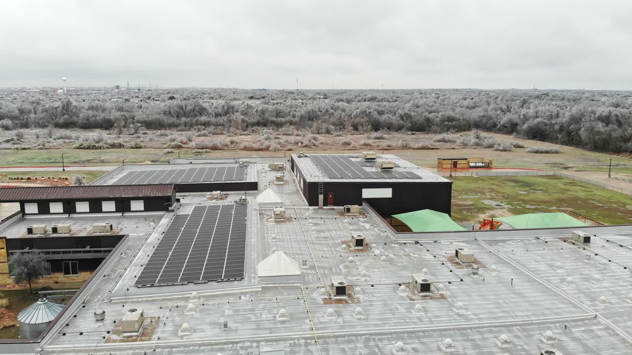 volando sobre la parte superior de una escuela primaria que tiene muchos paneles solares en el techo