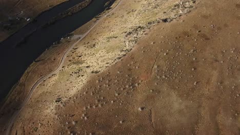 Aerial-view-of-a-river,-road,-and-hills-then-panning-up-to-mountains