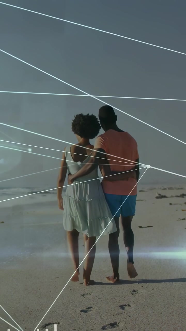 Vertical video: Man wrapping arm around woman, walking beach showing romance, tech tracing prints