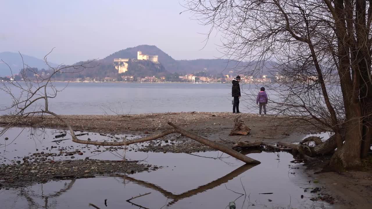 Mother and child on shore of lake Maggiore in Italy and Angera castle