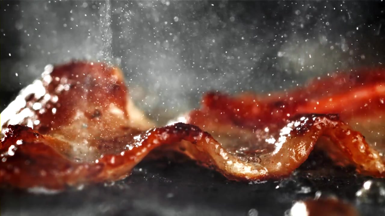 Nærbillede af bacon, der steger og syder på en varm pande