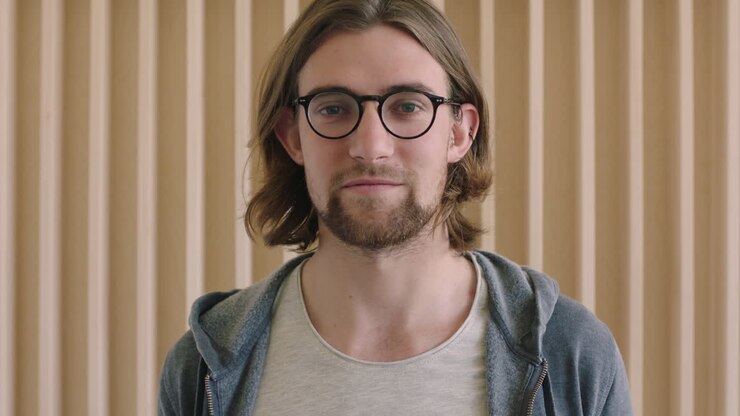 close up portrait of cute geeky man wearing glasses looking pensive serious at camera