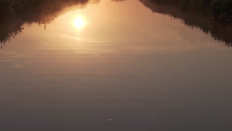 Reveal-shot-of-low-fog-above-small-ditch-at-Zaanse-schans-Holland,-aerial