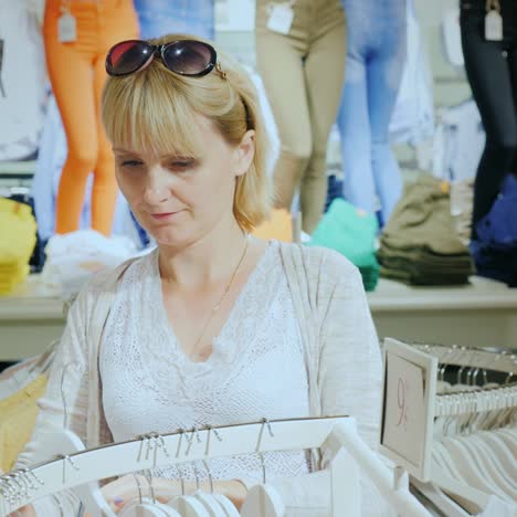 a young woman chooses summer clothes in the store