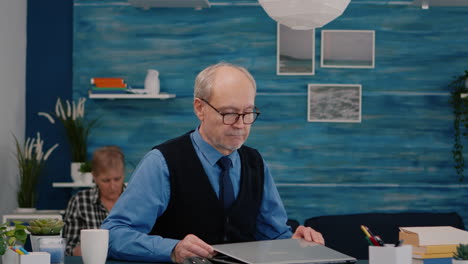 Elderly-man-freelancer-opening-laptop-squinting-while-reading-emails