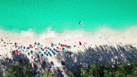 Overhead-4K-Drohnenclip-Eines-Sandstrandes-Mit-Smaragdgrünem-Wasser,-Tosenden-Wellen-Und-Bunten-Sonnenschirmen