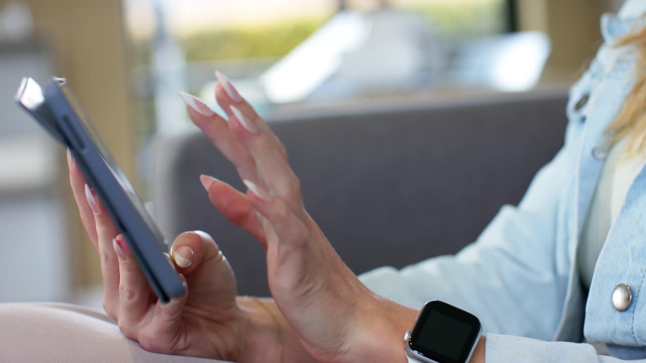 Woman is settling tablet on sofa, tapping, swiping and pinching screen while navigating content