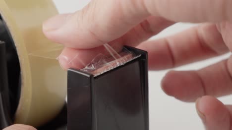a person's hands using a tape dispenser