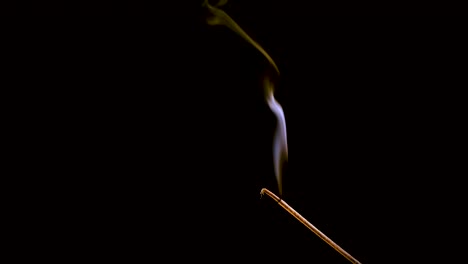 an incense stick burns and smokes.