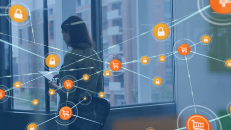 animation of network of connections with icons over caucasian businesswoman using tablet at office