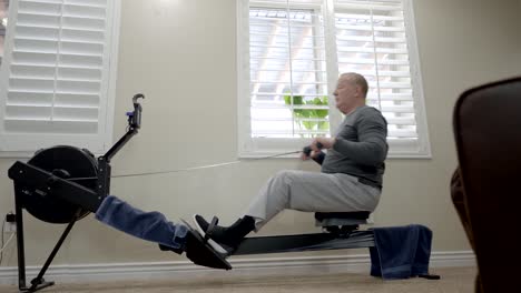 senior overweight man exercising on a rowing machine at home