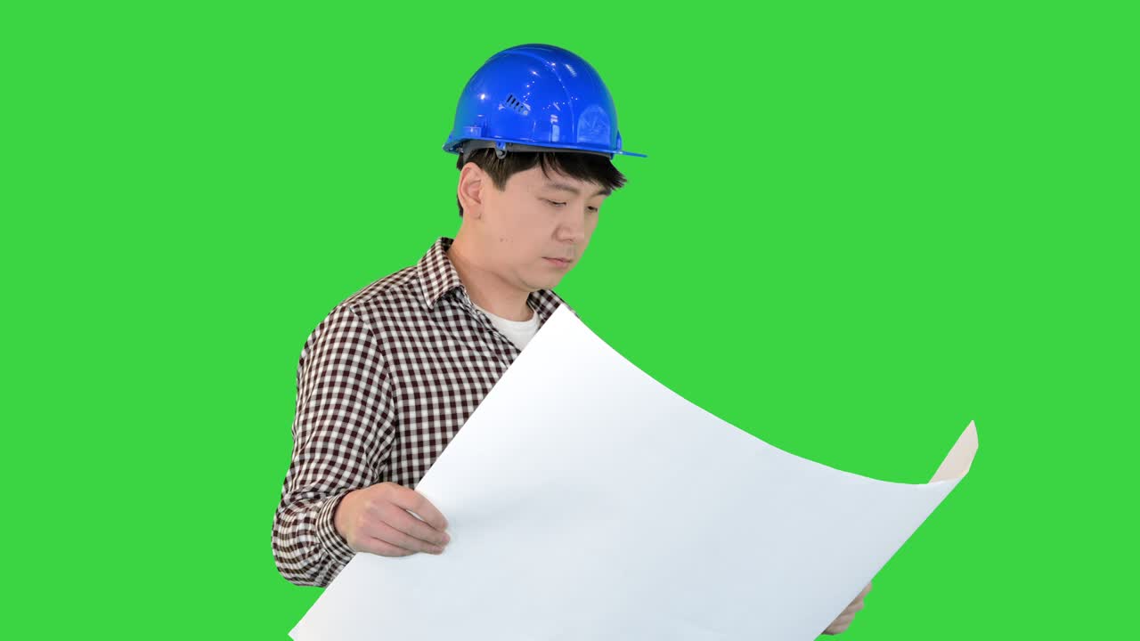 Engineer walking and looking at blueprint on a Green Screen, Chroma Key