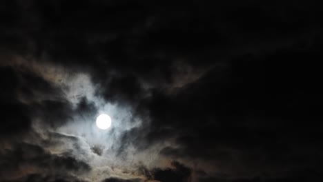 slow timelapse of rising full moon behind broken clouds, copy space