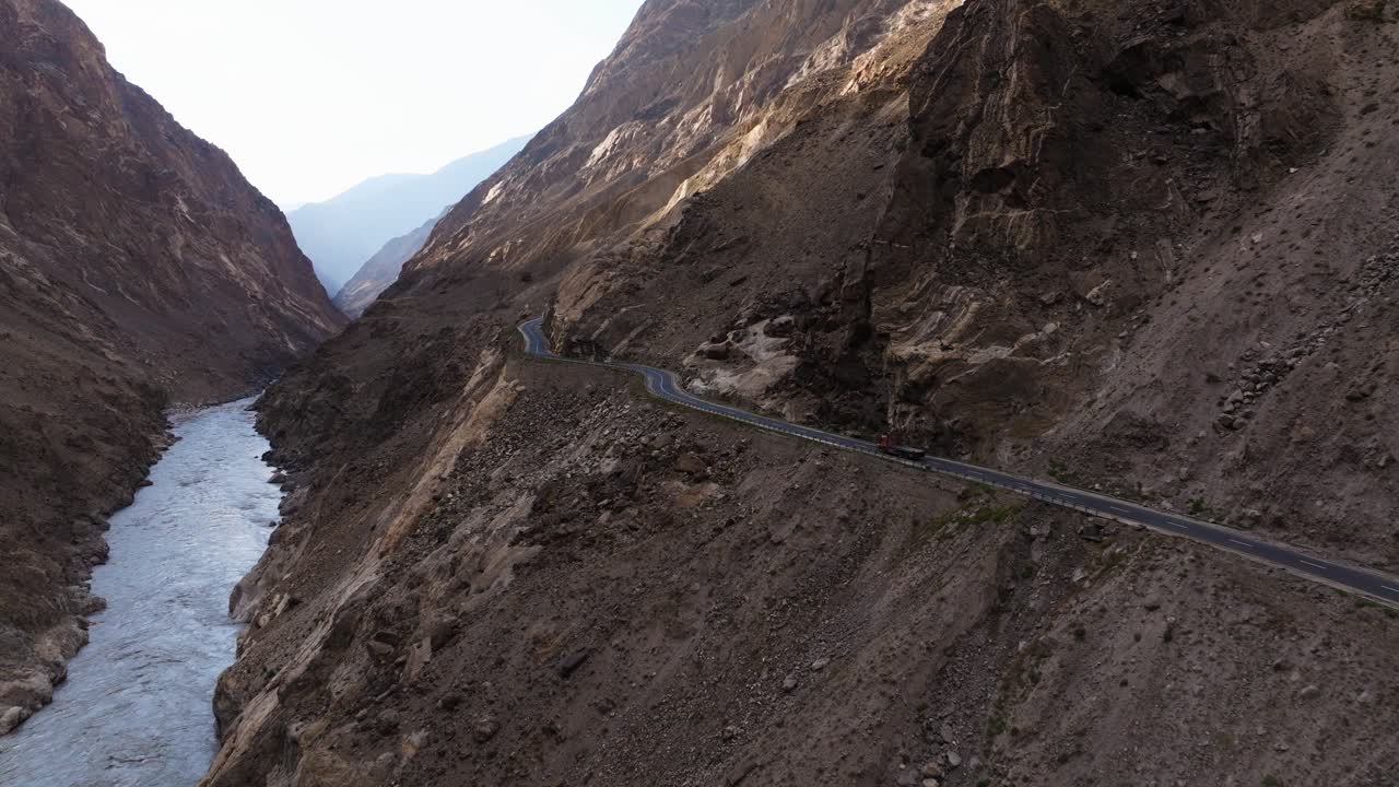 Scenic aerial footage showcasing the narrow road along the steep mountain sides, with the river carving through the rugged landscape below.