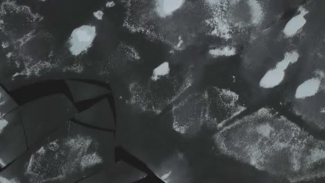 drone shot flying over frozen lake covered in ice and snow flying downward towards chunks of ice