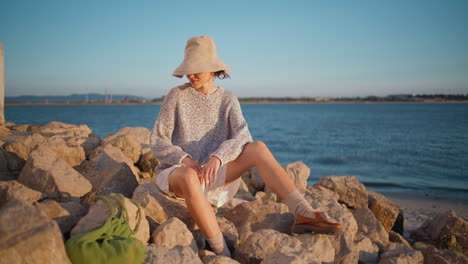 girl sunbathing shore rocks in evening. relaxed travel woman warming in sunlight