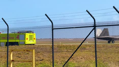 an f-22 raptor taxis on a runway at avalon airshow, geelong. bright daylight, with a fire truck visible in the background