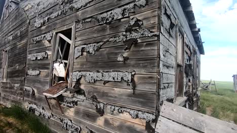the outside of a wooden old abandoned house in the country looking into the window.