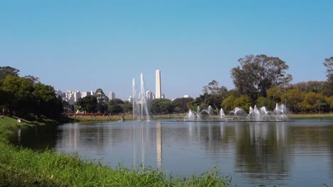 panorámica del lago y las fuentes del parque ibirapuera, con paisaje urbano y obelisco en la parte posterior