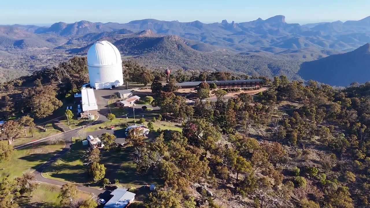 Ampia ripresa aerea con drone di cupole di telescopi in cima a una montagna nel Parco Nazionale Warrumbungle, Australia