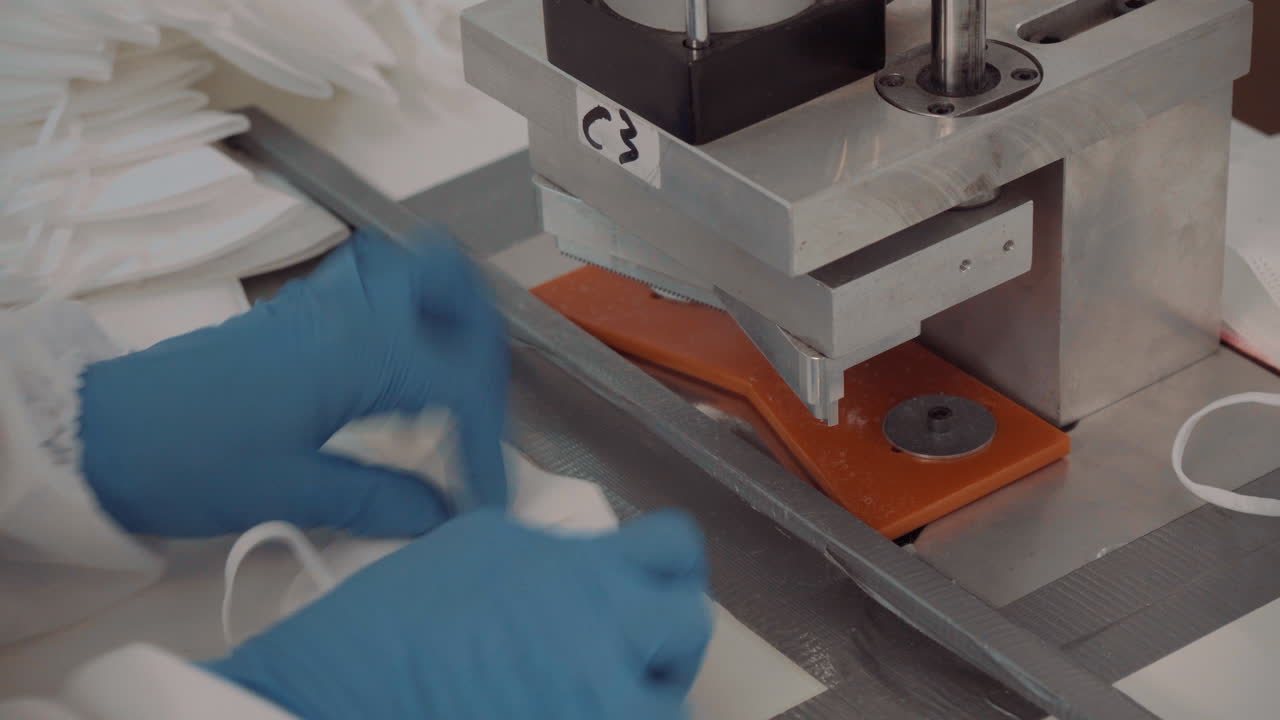 un hombre con traje protector y guantes vertió máscaras faciales en una máquina automática