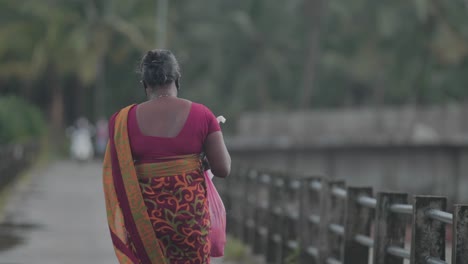 Indian-women-caring-groceries-in-plastic-cover-along-bridge-during-rainy-session