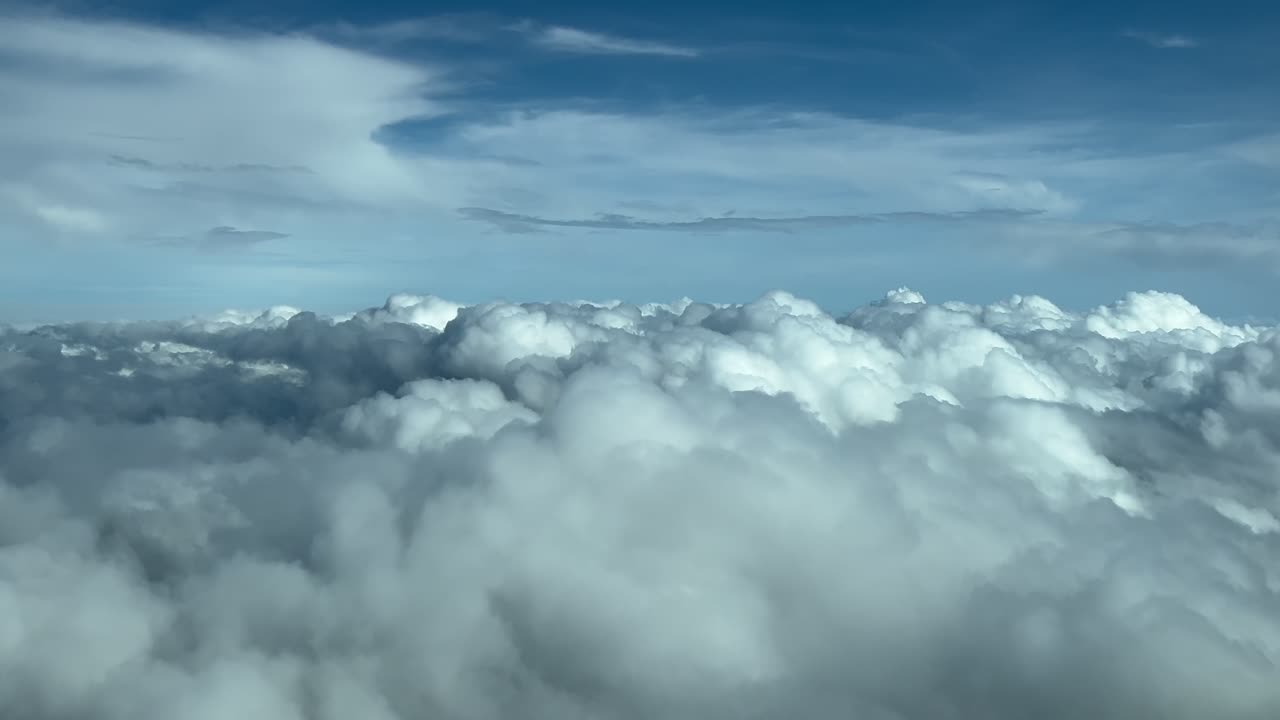 immersive POV flying ove a sea of stratus clouds as seen by the pilots of a jet from the cabin. Daylight, blue sky. 4K 60FPS