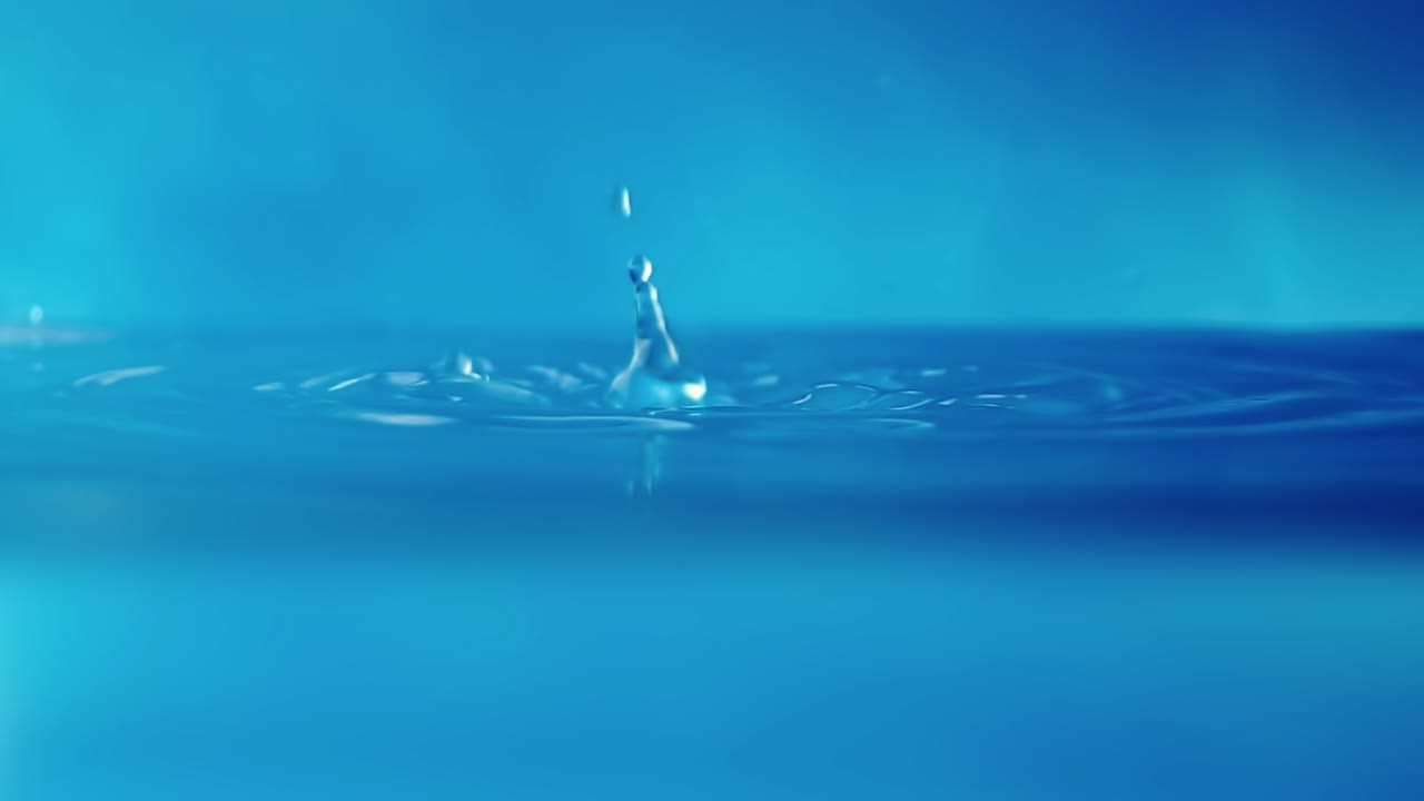 파란색 배경에 떨어지는 물방울과 함께 물 표면의 느린 모션 4k 비디오.