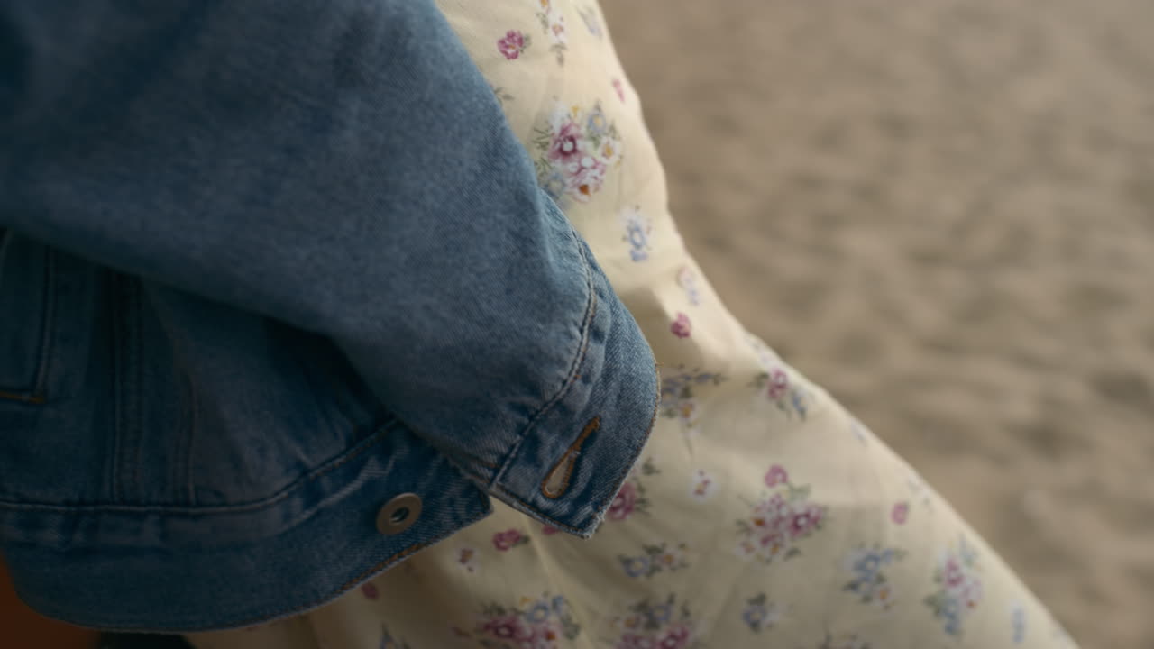 모래 해변에서 꽃 같은 드레스를 입은 여성의 몸. 바 ⁇ 가에서 혼자 서 있는 소녀.