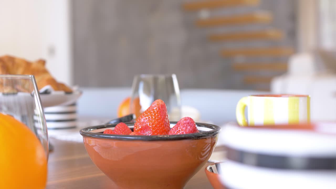 disparo de rotación lenta que muestra fresas recién recogidas en la mesa esperando ser comidas