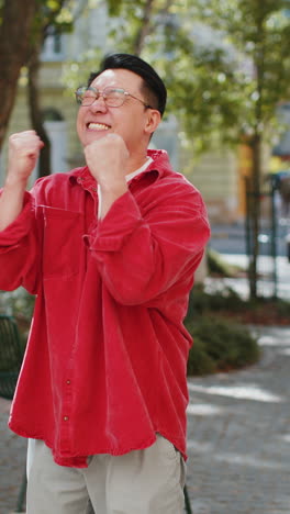 asian man shouting celebrating success winning goal achievement good victory news on city street