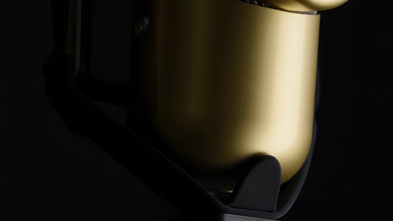 Close-up view captures subtle rotation of polished gold surface with changing reflections, curved contours, and dark surrounding space creating elegant minimal composition