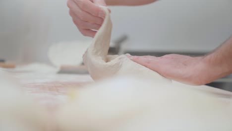 Baker-kneading-and-folding-dough-to-prepare-pie-in-a-bakery