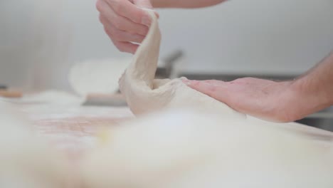 panadero que amasa y dobla la masa para preparar pasteles en una panadería