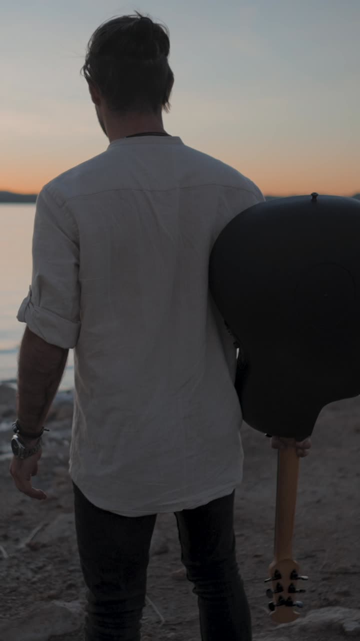 Man with Guitar at Sunset by the Water