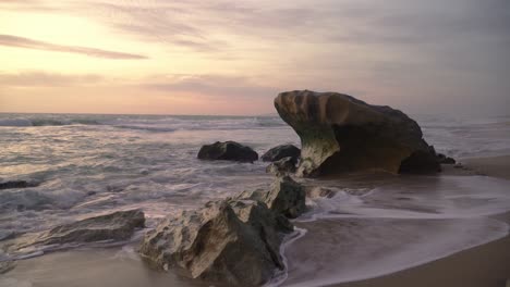 rough sea with waves breaking against rocks in the beach