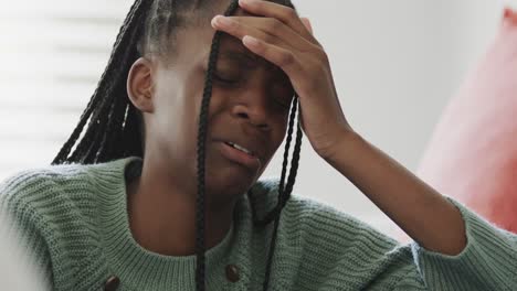 Sad-african-american-teenage-girl-sitting-on-bed-and-crying-at-home