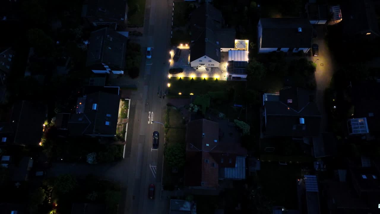 Lighting lantern and lights on streets and Houses of american neighborhood. Aerial top down flyover. Night scene with parking cars in small city of USA.